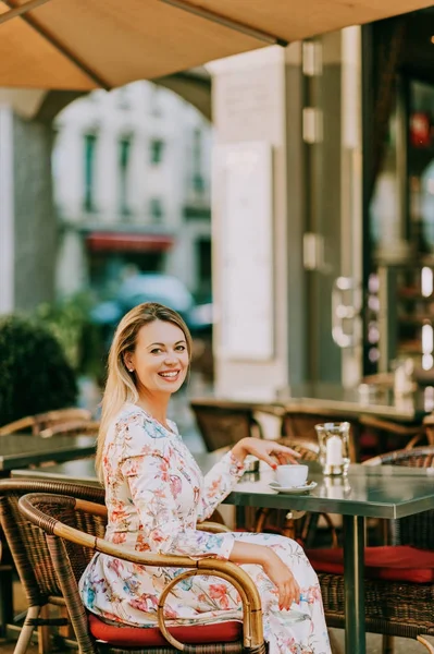 Retrato al aire libre de una hermosa mujer descansando en la cafetería con una taza de café —  Fotos de Stock