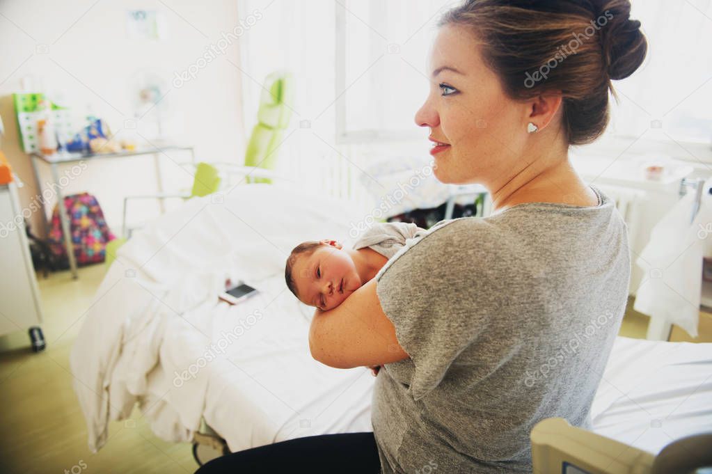 Happy young mother with newborn baby in hospital after giving birth