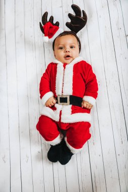 Beyaz arka plan üzerinde yalan bebek çocuk Noel baba nın kıyafeti ve Ren geyiği kulak, üstten görünüm giyen Noel portresi