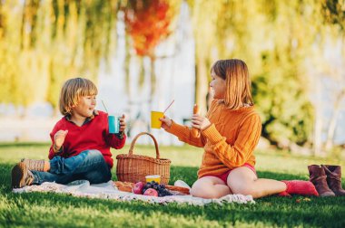 Çocuklar dışında abur cubur yeme. Çocuklar parkta güzel bir güneşli gün battaniye var oturma dinlenme