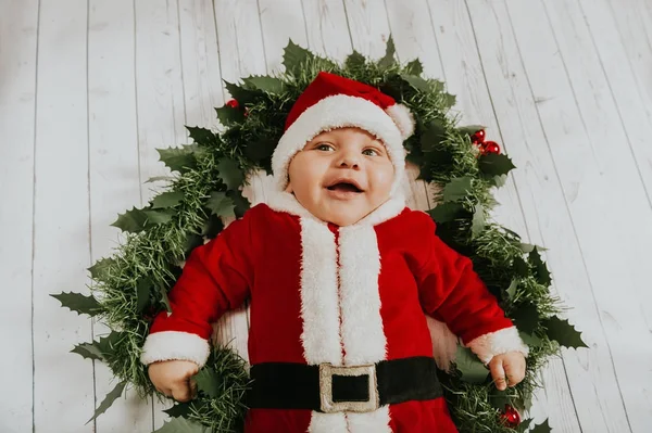 Estúdio tiro de menino adorável vestindo roupa de Papai Noel, deitado no fundo branco na decoração de Natal, vista superior — Fotografia de Stock