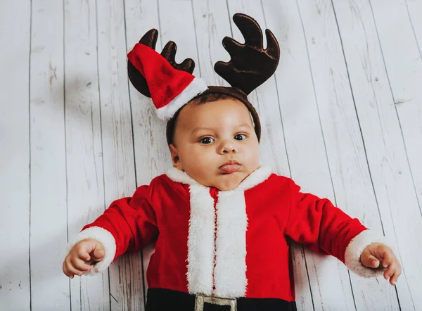 Retrato de Natal de menino adorável deitado no fundo branco, vestindo roupas de Papai Noel e orelhas de rena, vista superior — Fotografia de Stock