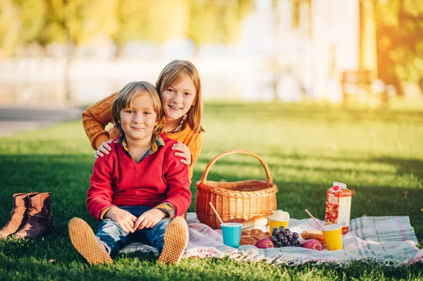 Miúdos a comer snacks lá fora. Crianças descansando no parque em um dia ensolarado agradável sentado no cobertor — Fotografia de Stock