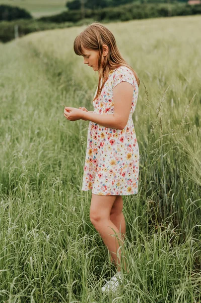 Kleines Mädchen, das im Sommer im grünen Weizenfeld spielt und ein Kleid trägt — Stockfoto