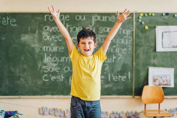 Criança feliz trabalhando em sala de aula, mãos levantadas, educação, de volta ao conceito de escola — Fotografia de Stock