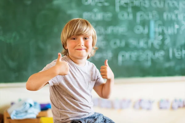 Criança feliz trabalhando em sala de aula, polegares grandes para cima, educação, de volta ao conceito de escola — Fotografia de Stock