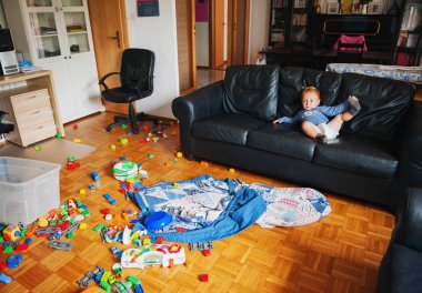 Çok güzel 1 yaşındaki bebek çocuk çok pis bir oturma odasında oynarken, bir koltukta yalan, tv izlerken komik yüz ifadesi ile