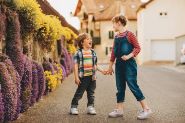 Birlikte açık havada güzel bir güneşli akşamı oynayan iki şirin mutlu genç çocuklar, ellerimi. Küçük kardeş ve birlikte vakit abla