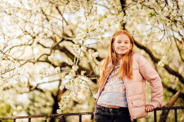 ピンクのパッド入りのジャケットを着て咲くりんごの木と外で遊んで喜んでいる子供女の子 — ストック写真