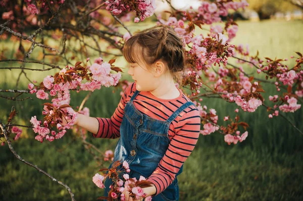 花で日本の桜の花の間に立って かわいい女の子の露天の肖像画 — ストック写真