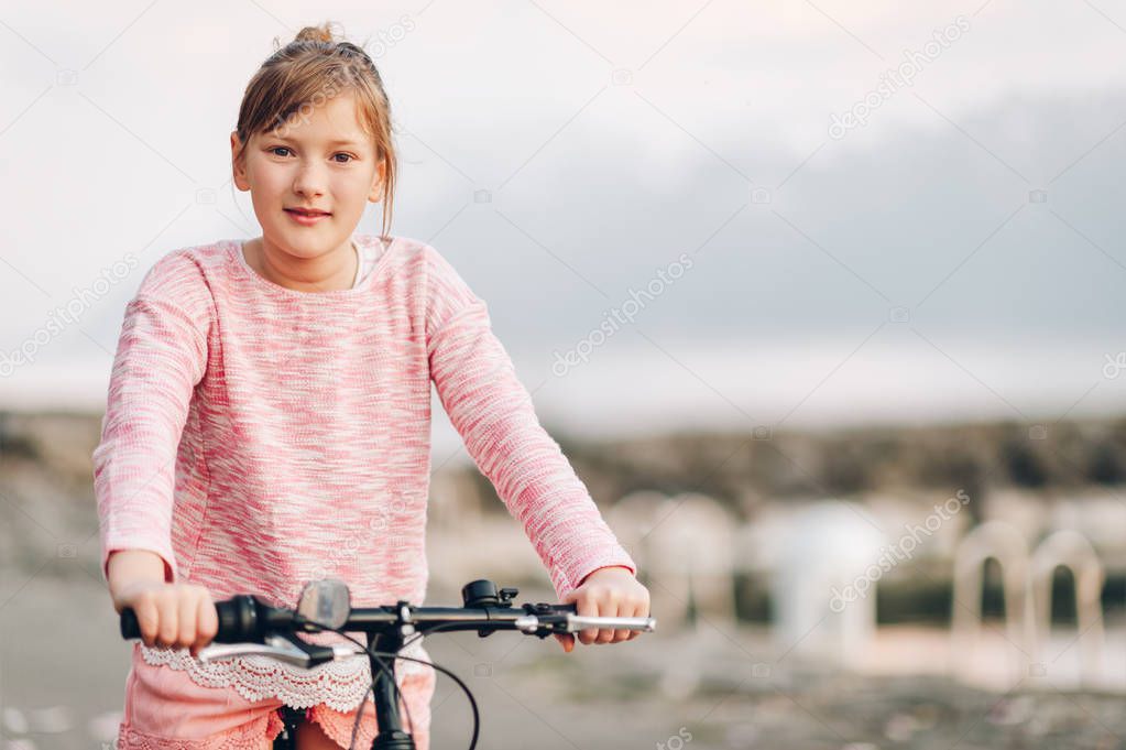 Pretty kid girl riding bicycle next to lake, activities for children