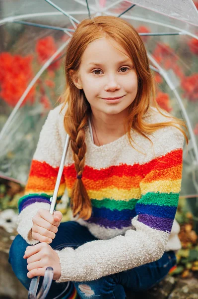 虹プルオーバー 女の子のためのファッション 雨の日に外で遊ぶ子を着て透明傘を持ってかわいい赤毛の子供女の子の露天の肖像画 — ストック写真