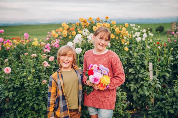 秋の庭で撚る ダリアの花の花束を持って つの面白い子供の屋外のポートレート — ストック写真