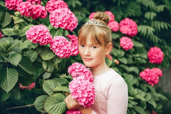 チュチュ ドレスとプリンセスの王冠を身に着けているアジサイの庭で遊ぶ愛らしいバレリーナ少女の肖像画 — ストック写真