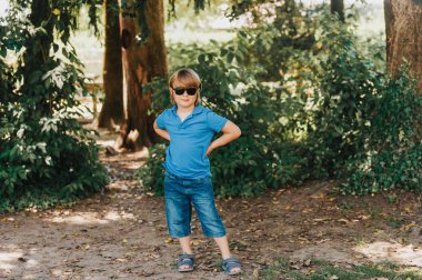 Açık mavi polo ve moda güneş gözlüğü takıyor sevimli küçük çocuk portresi