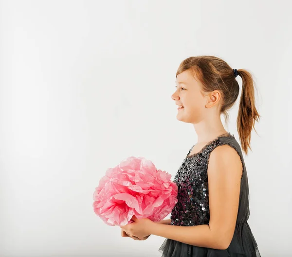 かわいい子供女の子白い背景で撮影した灰色のパーティー ドレスを着て 大きなピンクの紙の花の装飾を保持のスタジオ撮影 — ストック写真