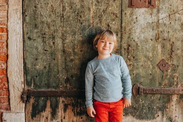 赤いチノパンと光の青いプルオーバー スタイリッシュな子供ヴィンテージの古い壁に対してポーズを身に着けているハンサムな男の子の屋外のポートレート 小さな子供のためのファッション — ストック写真