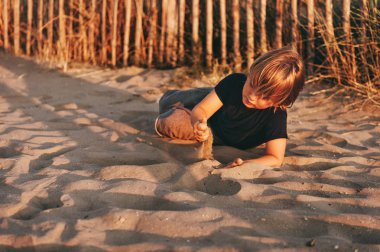 Komik çocuk çocuk deniz kum plajı üzerinde günbatımında dinleniyor. Genç çocuk Güney Fransa yaz tatilinin tadını çıkarıyor