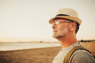 Şapka, gözlük ve sırt çantası giyiyor yakışıklı yaz tatilde deniz kenarında