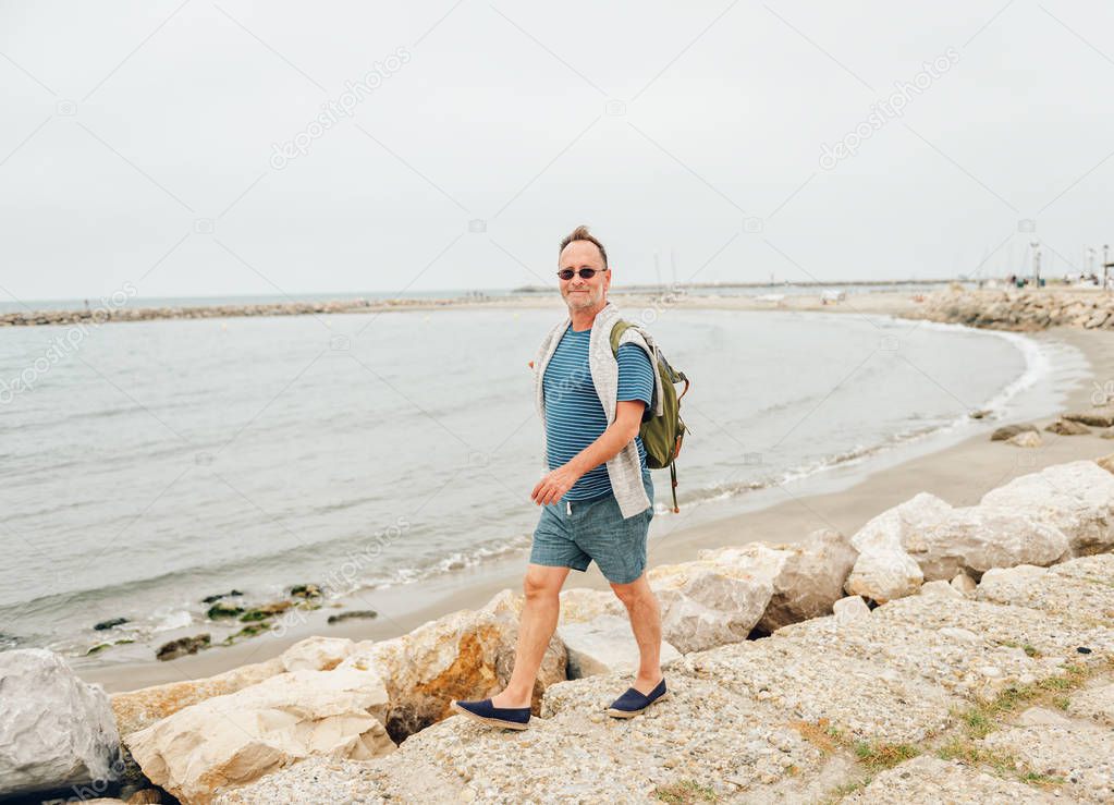 Man enjoying summer vacation by the sea, wearing stripe nautical t-shirt and backpack. Image taken in Saintes-Maries-de-la-Mer, capital of Camargue, south of France