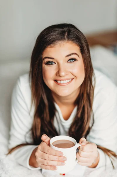 Retrato Interior Una Joven Feliz Relajándose Dormitorio Usando Pijamas Sosteniendo — Foto de Stock