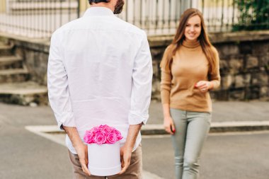 Genç ve güzel bayana pembe güller sunan bir adam