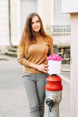 Güzel bir kadının açık hava portresi. Elinde pembe güller olan bir kutu.