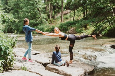 Genç, zinde bir anne, kızlarıyla, sportif ailesiyle doğada pratik yapıyor.