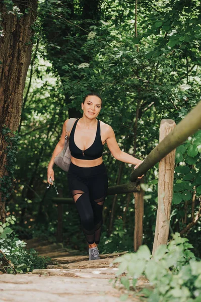 Подходящая Молодая Женщина Лесу Взбирающаяся Лестнице Одетая Черную Спортивную Одежду — стоковое фото