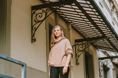 Bej rengi yaka kazak giyen güzel bir kadının sokak modası portresi.