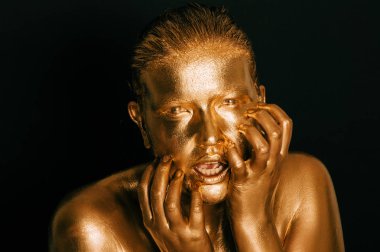 Altın boyayla kaplanmış genç ve güzel bir kadının resmi.