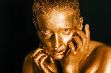 Altın boyayla kaplanmış genç ve güzel bir kadının resmi.