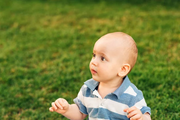 Outdoor portrait of adorable baby boy playing in summer parc