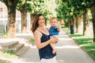 Mutlu bir annenin açık hava portresi kucağında sevimli bir oğlan çocuğu.