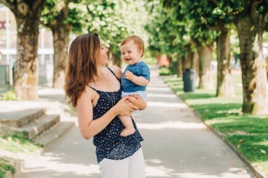 Mutlu bir annenin açık hava portresi kucağında sevimli bir oğlan çocuğu.