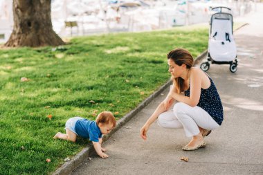 Mutlu anne çocuklarla yaz parkında vakit geçiriyor, bebekle oynuyor.
