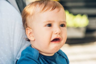 Üzgün bir bebeğin at arabasında otururken çekilmiş yakın portresi.