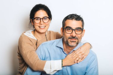 Gözlük takan, beyaz arka planda birlikte poz veren mutlu çiftin stüdyo portresi.