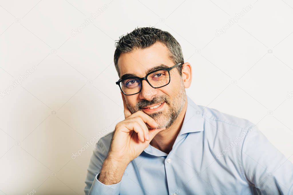 Studio portrait of handsome man wearing formal blue shirt and glasses, posing on white background