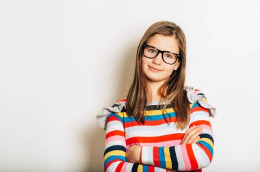 Gözlüklü ve renkli çizgili uzun kollu gömlek giyen güzel bir kızın stüdyo portresi.
