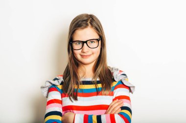 Gözlüklü ve renkli çizgili uzun kollu gömlek giyen güzel bir kızın stüdyo portresi.