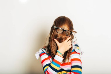 Studio portrait of young girl fooling around, hiding behind, hair, acting silly, time for haircut, hair completely covering the face with glasses over clipart