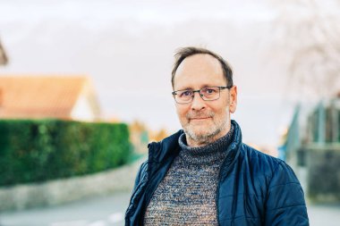 Gözlük takan orta yaşlı bir adamın açık hava portresi.