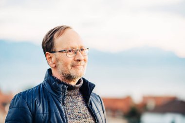 Gözlük takan orta yaşlı bir adamın açık hava portresi.