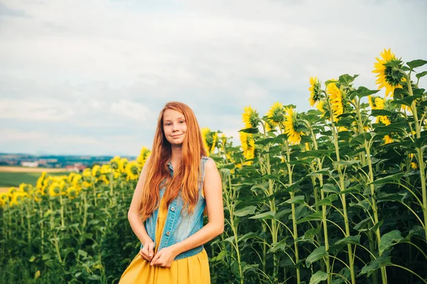 ひまわり畑にポーズをとる可愛い若い赤髪の女の子の屋外肖像画 — ストック写真