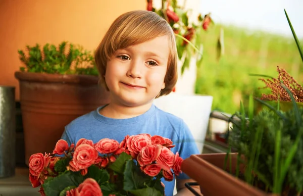 ピンクの花とバルコニーの保持鍋にかわいい幼児の男の子 小さな庭師 — ストック写真