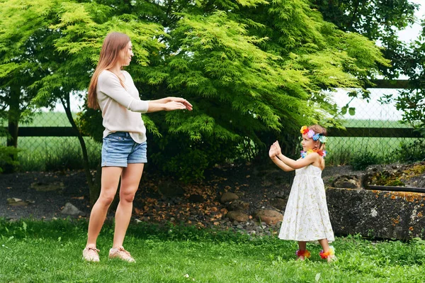 年轻妈妈和可爱的小女儿在花园里跳舞 一家人在一起消磨时光 — 图库照片