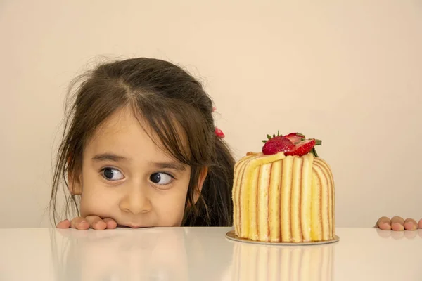 Little girl looking at cake and is surprised
