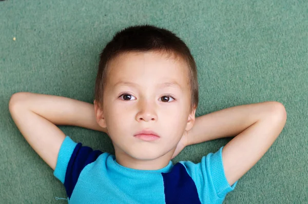 Portret van de nadenkende jongen liggend op gekruiste armen — Stockfoto