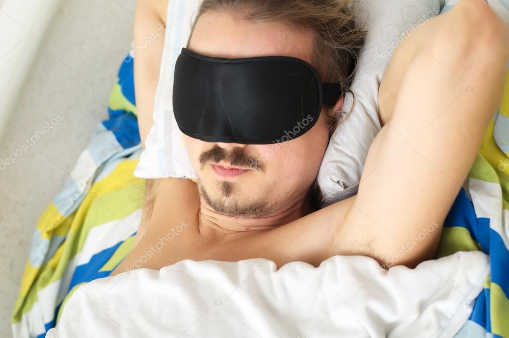 young mustached husband sleeping with sleep mask